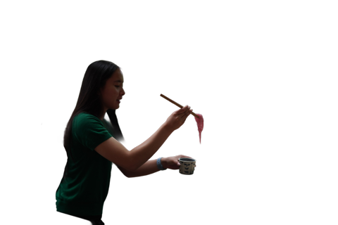 A person with long hair lifts a dripping pink substance with chopsticks over a patterned cup against a black background.